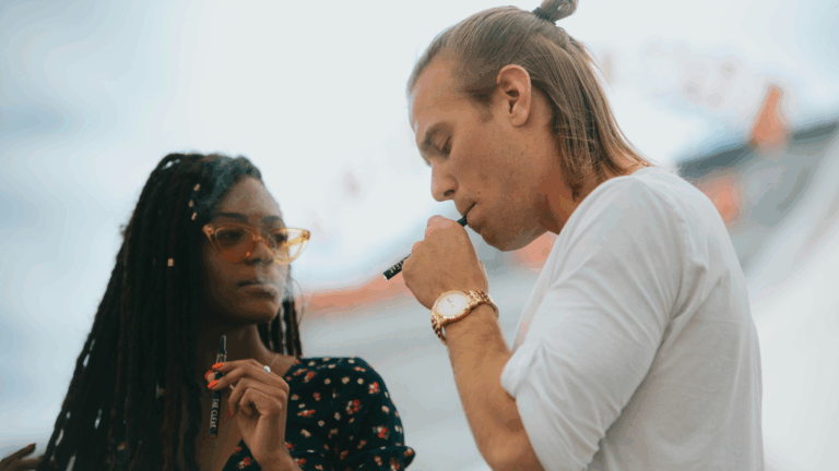 A man and woman hitting dab pens outdoors