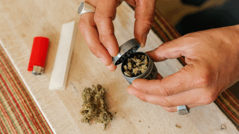 Person grinding THCA flower in a silver grinder