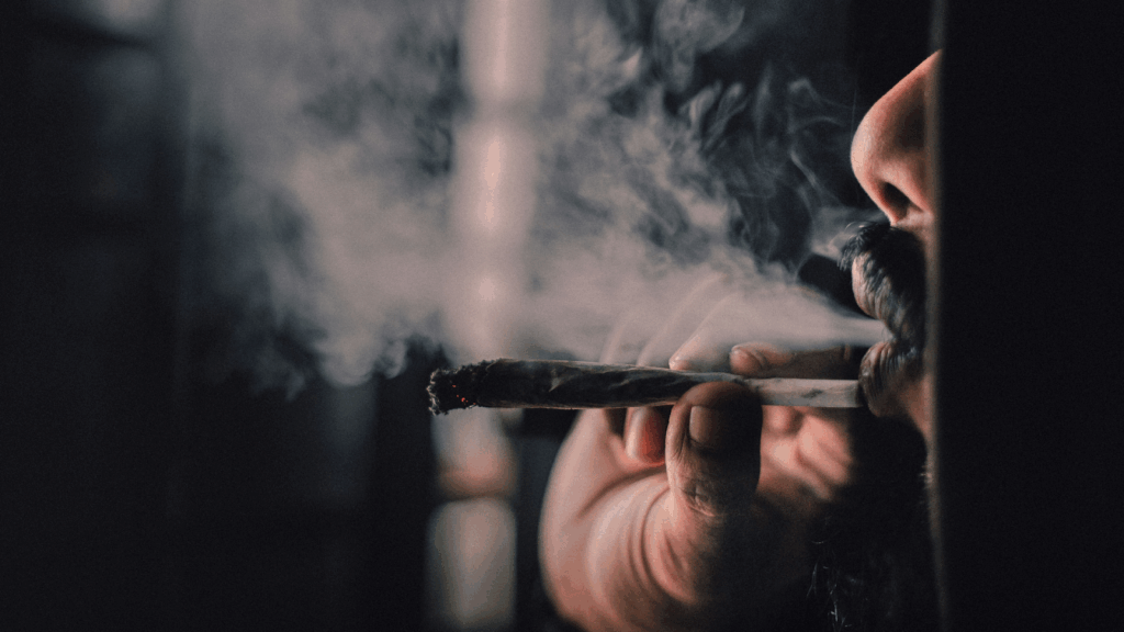 Side-view of a man exhaling smoke from a joint